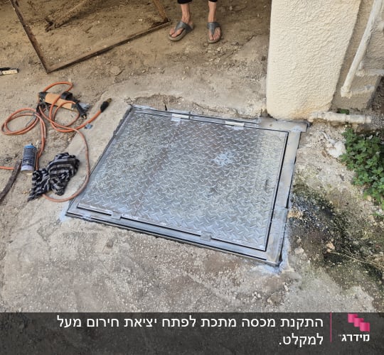 פתח מתכת על הקרקע עם כלים מסביב